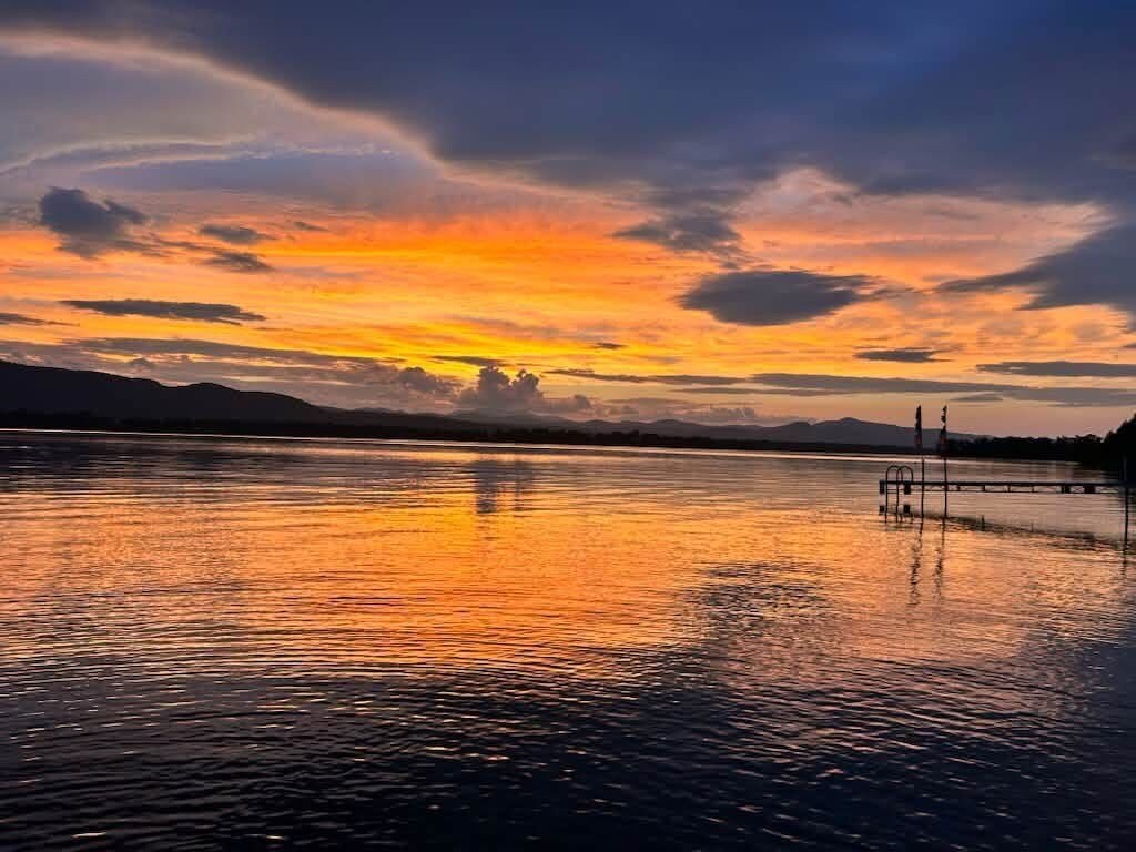 A calm body of water reflecting a sunset sky.
