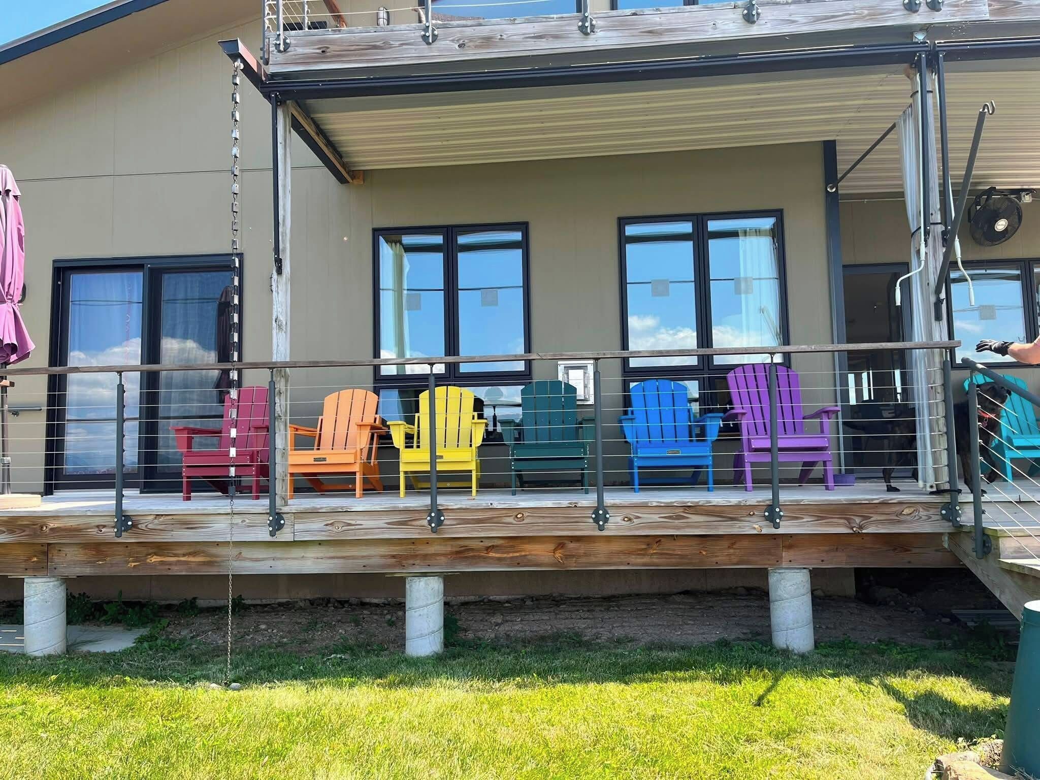 A covered outdoor seating area with colorful Adirondack chairs and a wooden deck.