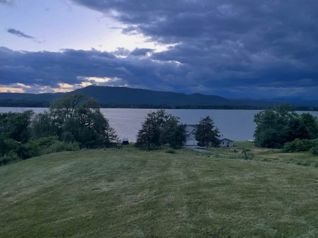En græsmark med en sø og bjerge i baggrunden.