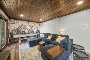 Ein stilvolles Wohnzimmer mit einem Ecksofa, einer Holzbalkendecke und einem großen Wandbild.