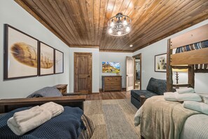 Ein Zimmer mit Holzbalkendecke, einem Bett mit blauer Decke, einem Sofa, einer Holzkommode und einem Bild an der Wand.