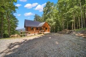 Eine Blockhütte mit Kiesauffahrt, umgeben von einem Wald.