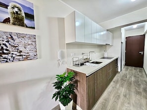 A modern kitchen with white cabinets, a wooden countertop, and a sink. There is a potted plant on the counter. - Barranco Luxe | A/C • Rooftop Pool & Hot Tub • Gym ⭐ (Barranco)