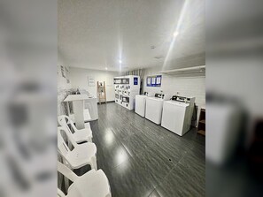 A laundry facility with multiple washing machines, drying machines, and a seating area with chairs. - Barranco Luxe | A/C • Rooftop Pool & Hot Tub • Gym ⭐ (Barranco)
