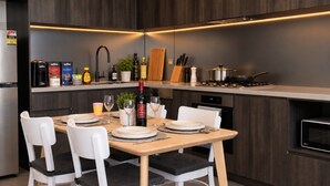 Et moderne køkken med spiseplads, udstyret med komfur, vask og diverse hårde hvidevarer.