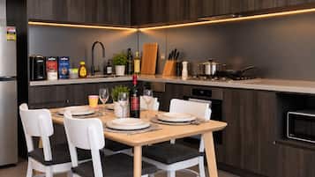 Een moderne keuken met een eethoek, voorzien van een kookplaat, spoelbak en diverse keukenapparaten.