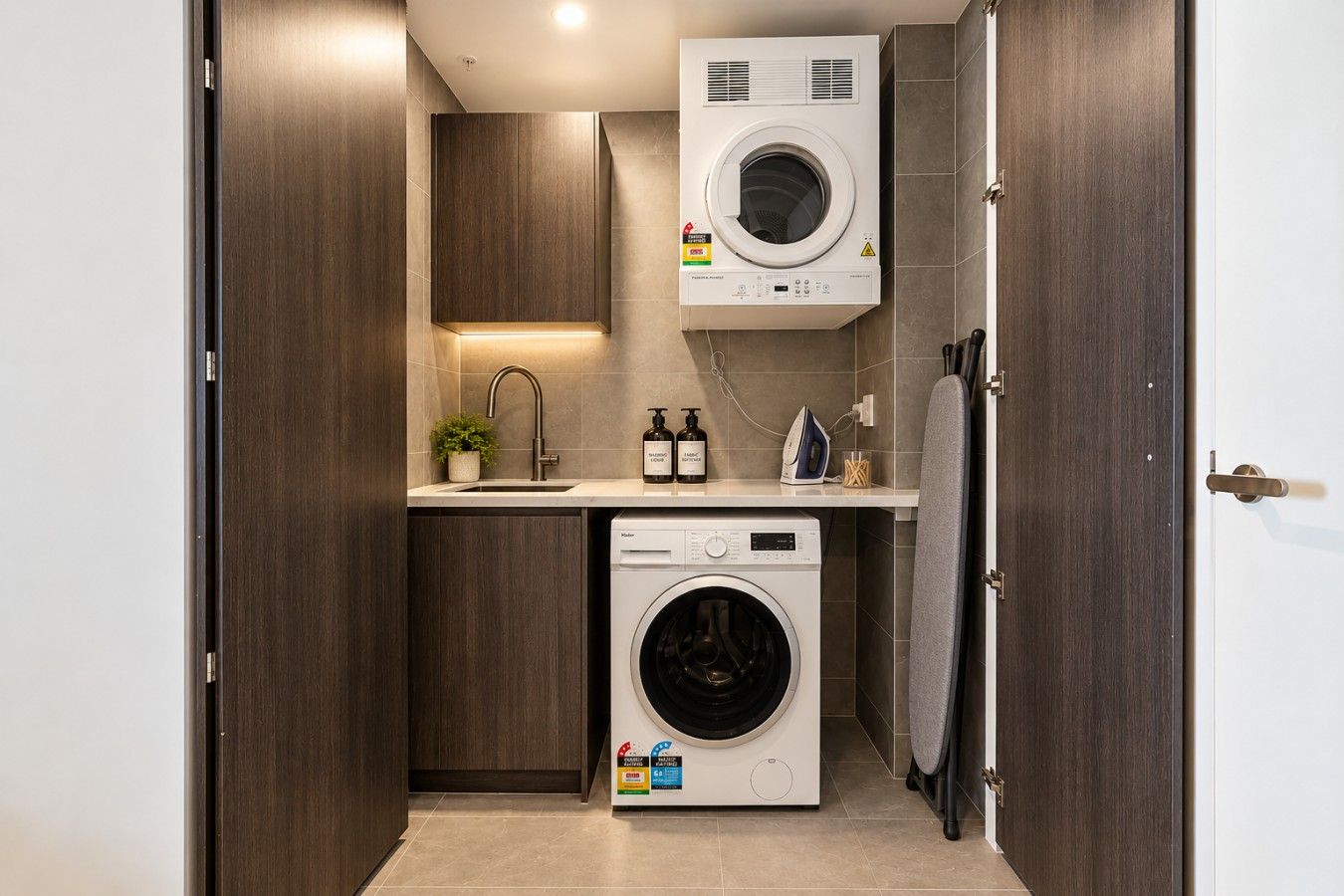 A compact laundry room with a washing machine, a dryer, and a small sink.