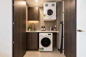 A compact laundry room with a washing machine, a dryer, and a small sink.