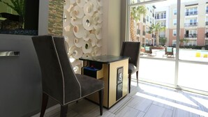 Un interior moderno con un escritorio, dos sillas, una pared decorativa y vistas al exterior.