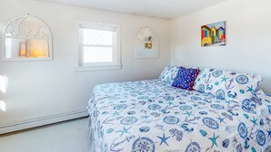 Un dormitorio con cama, dos ventanas y un cuadro colgado en la pared.