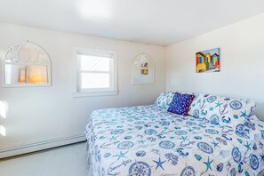 Ein Schlafzimmer mit einem Bett, zwei Fenstern und einem an der Wand hängenden Bild.