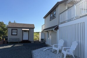 A two-story building with a gravel driveway and white outdoor chairs. - Gorgeous Family Rental - Steps to Sagamore Beach (Sandwich)