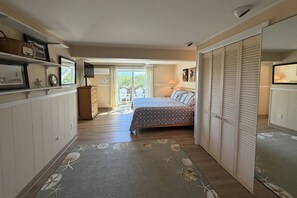 A bedroom with a bed, a wardrobe, a dresser, a television, and a view of the outdoors. - Gorgeous Family Rental - Steps to Sagamore Beach (Sandwich)