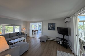 A living room with a sofa, a coffee table, a TV, and a window. - Gorgeous Family Rental - Steps to Sagamore Beach (Sandwich)