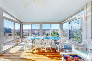 A sunroom with a table and chairs, large windows, and a view of the outdoors. - Gorgeous Family Rental - Steps to Sagamore Beach (Sandwich)