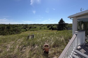 A grassy field with a wooden fence and a building with a balcony.