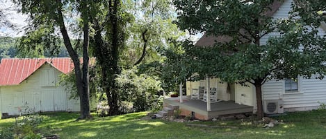 Ein Wohnhaus mit Rasen, einem Gartenhaus mit rotem Dach und einer Veranda.