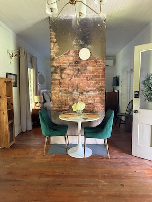 Un comedor con pared de ladrillo, una mesa redonda con dos sillas y una lámpara de techo.