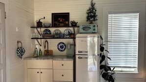 A compact kitchen with a white refrigerator, a toaster, and a hanging light fixture.