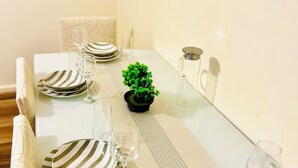 Ett matbord dukat med randiga tallrikar, glas och en liten krukväxt.