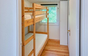 Ein Stockbett in einem schmalen Zimmer mit Fenster und Tür.