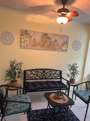 A living room with a sofa, two chairs, a coffee table, and decorative plants.