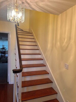 A wooden staircase with white railings and a chandelier.