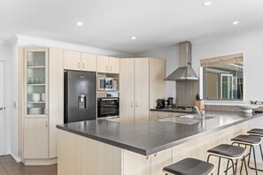 A modern kitchen with a central island, built-in appliances, and a large window. - Family Ski Base | Boot Dryer | 4Bedroom (Wānaka)