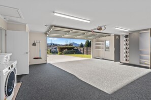 A laundry room with a washing machine, drying racks, and a view of a residential area. - Family Ski Base | Boot Dryer | 4Bedroom (Wānaka)