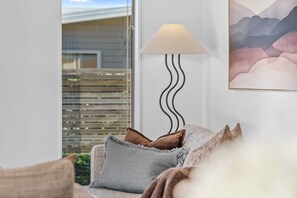 A living room with a sofa, a lamp, and a painting on the wall. - Family Ski Base | Boot Dryer | 4Bedroom (Wānaka)