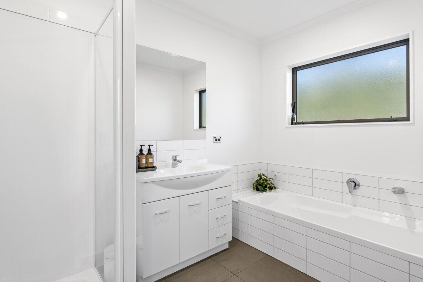 A modern bathroom with a white sink, vanity, and bathtub.