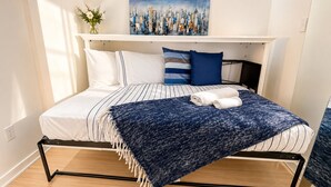 Ein Bett mit einer gestreiften Tagesdecke, einer blauen Zudecke und zwei Kissen.