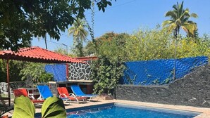 Une piscine avec des chaises longues et un espace de repos abrité.