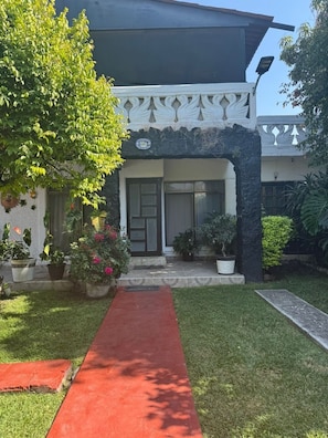 A building with a red pathway leading to the entrance, surrounded by potted plants and a well-maintained lawn. - Dianas Home Oaxtepec (México)