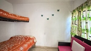 Une petite pièce avec un lit superposé, un canapé et un tapis à motifs.