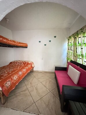 A small room with a bunk bed, a sofa, and a patterned rug.