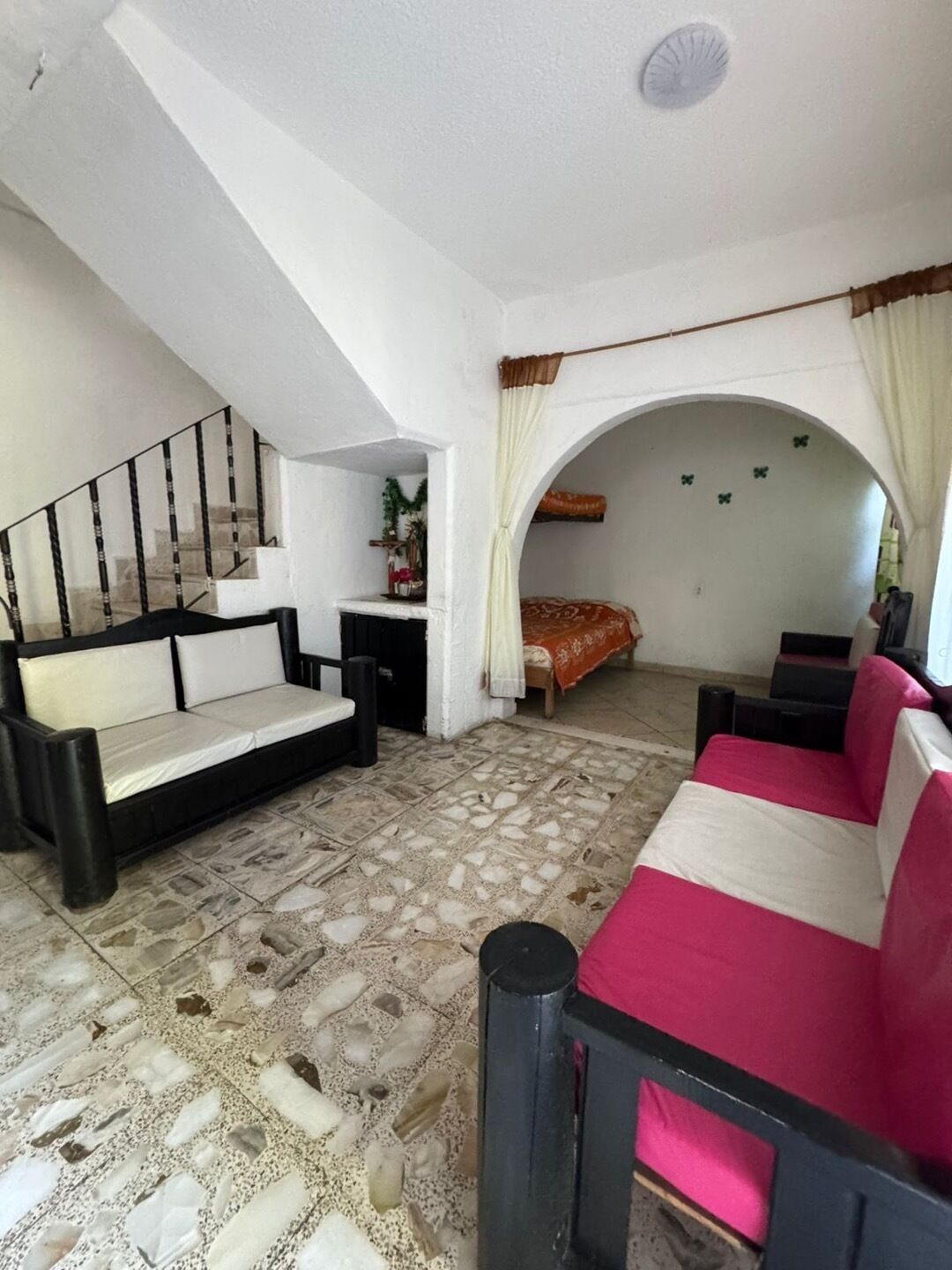 Una habitación con escalera, sofá, cama y una pequeña mesa.