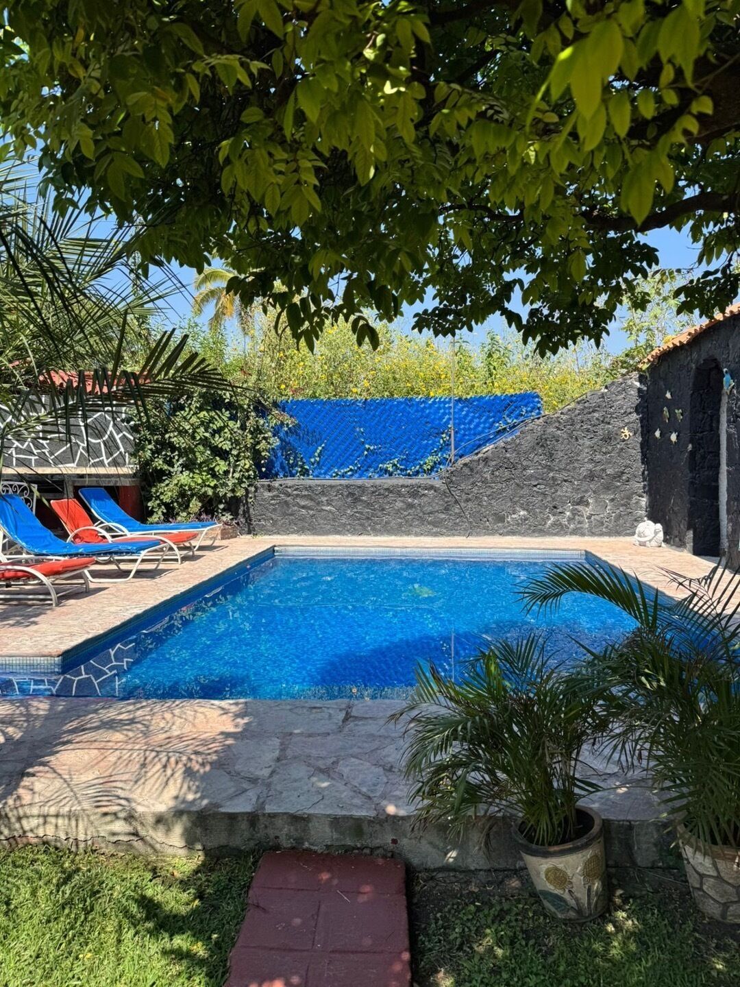 Una piscina con sillas de descanso y un muro de piedra.
