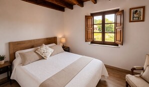 A bedroom with a wooden headboard, a bed with white bedding, a nightstand with a lamp, a window with wooden shutters, and a chair. - La Eugenia Country House · Picos de Europa · Cabrales (Pandiello (Cabrales))