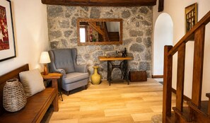 Ein gemütliches Wohnzimmer mit Steinwand, einer Holztreppe, einem Sofa, einer Lampe und einer Nähmaschine.