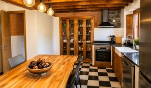 Eine Küche mit Holztisch, Schachbrettmuster-Boden und integriertem Backofen.