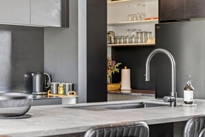 Una cucina moderna con lavello in acciaio inossidabile, bollitore e contenitori.