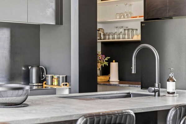 A modern kitchen with a stainless steel sink, a kettle, and canisters.