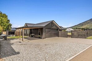 A modern building with a covered outdoor area, a gravel driveway, and a wooden fence.