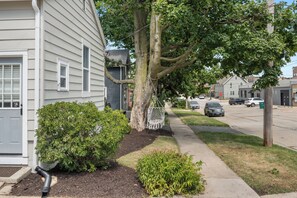 A residential street with houses, a sidewalk, and parked cars.