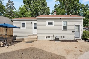 A single-story house with a front porch, a small attached garage, and a patio area with outdoor furniture.