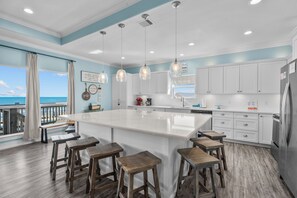 A modern kitchen with a large island, white cabinetry, and pendant lighting. - Beachfront Home in Crystal Beach | Private Hot Tub | Double Decks | Outdoor Bar | Sleeps 16 (Crystal Beach)
