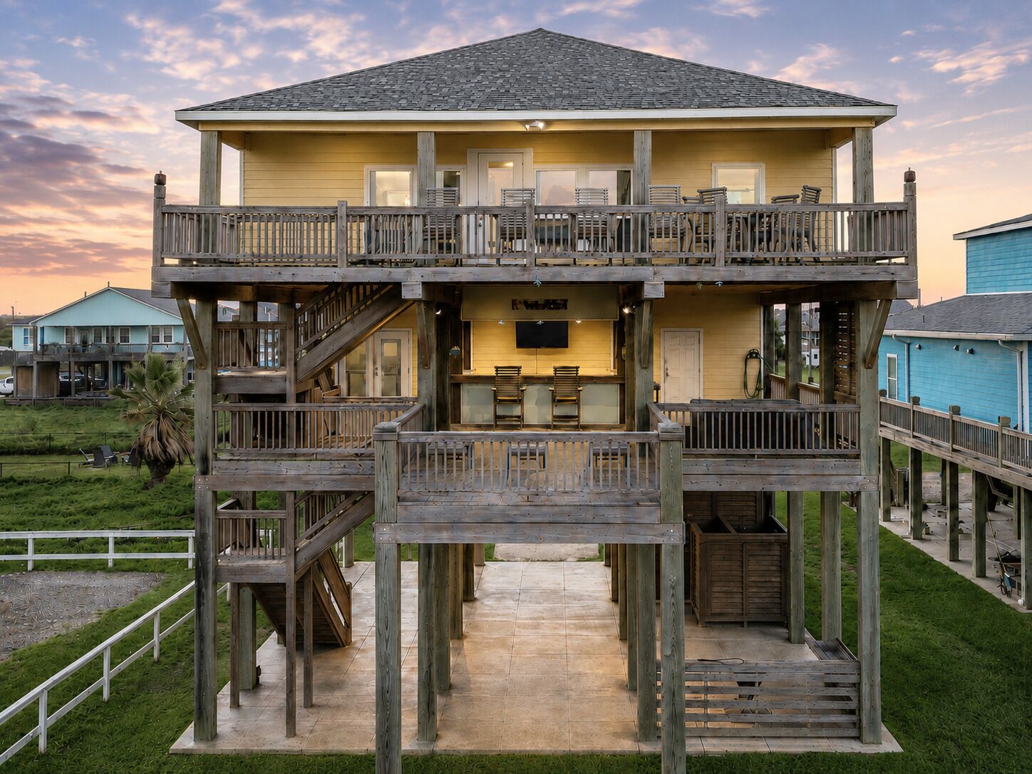 A two-story wooden structure with a balcony, a kitchen area, and a poolside deck.