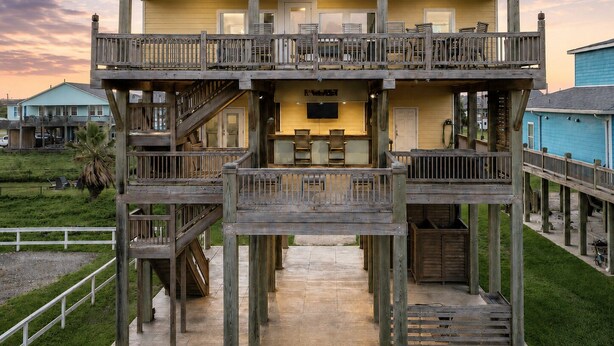Ein zweistöckiges Holzhaus mit einem Balkon, einer Küchenzeile und einer Poolterrasse.