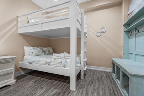 A bunk bed with a white frame, a bedside table, and a dresser with a light blue finish. - Beachfront Home in Crystal Beach | Private Hot Tub | Double Decks | Outdoor Bar | Sleeps 16 (Crystal Beach)